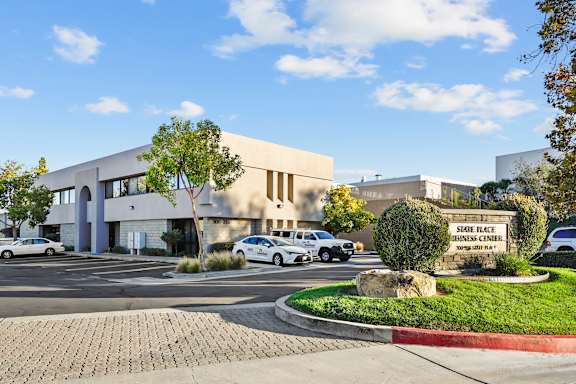 A building with a sign that says "Sample Place Business Center" in front of it.