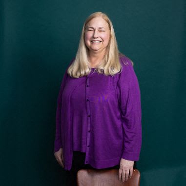 a woman smiling in front of some flowers