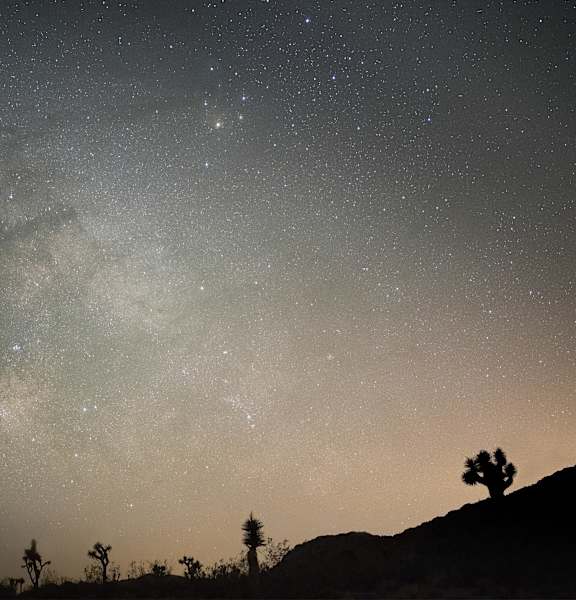 The Milky Way galaxy is visible in the night sky above a desert landscape.