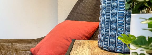 a chair with an orange pillow and a table with a plant at Convent Gardens Apartments, St. Louis, MO, 63108