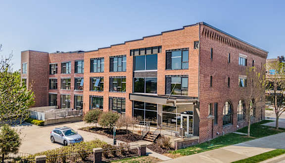 A large red brick building with a parking lot in front.