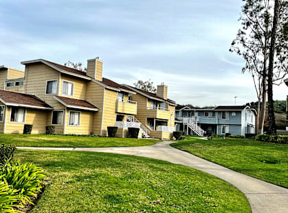 a row of houses on a grassy hill with trees in the background