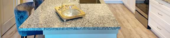 A kitchen with a granite countertop and blue chairs. at AVLI AT CROSSTOWN CENTER Apartments , TAMPA, FL, 33619