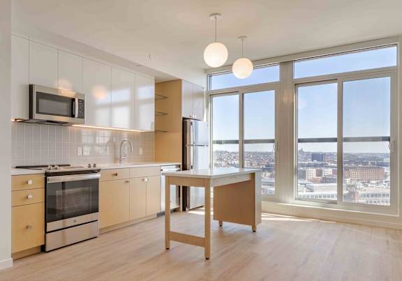 A kitchen with a microwave above the stove and a table in front of a window.