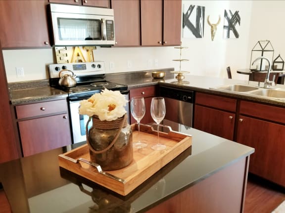 a kitchen with a wooden cutting board with a vase and glasses on a counter  at Aventura at Richmond, St. Peters