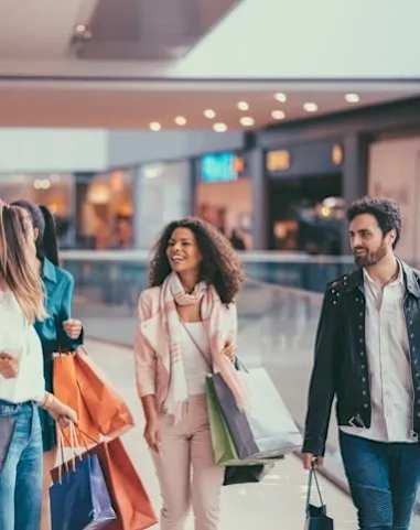 Three people walking in a mall carrying shopping bags.