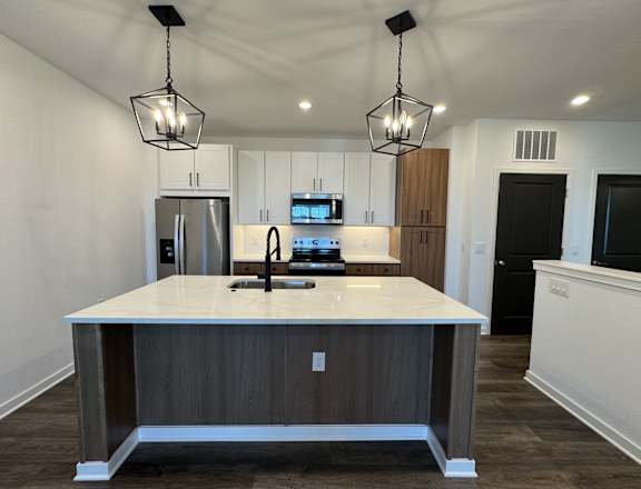 A modern kitchen with a center island and pendant lights.