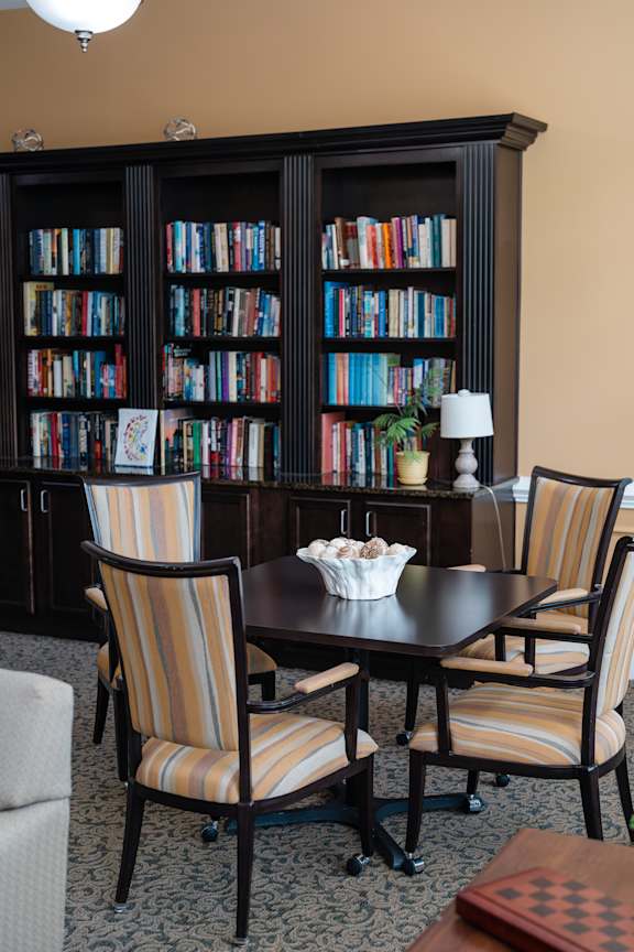 A room with a table, chairs and a bookshelf.