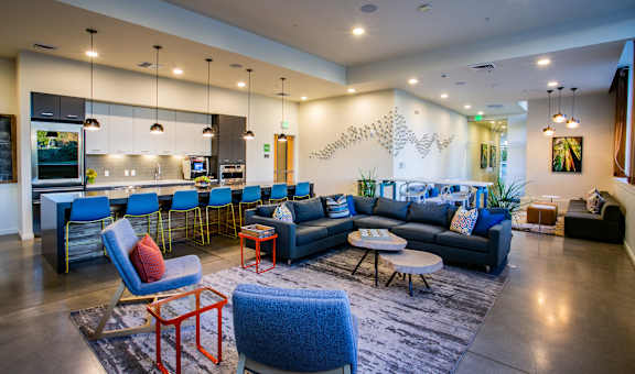 a living room with blue couches and chairs and a kitchen