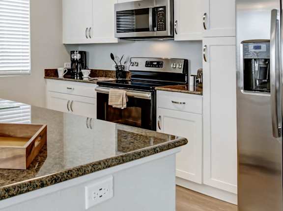 A kitchen with granite countertops and stainless steel appliances. at Apex Mission Valley, California, 92108