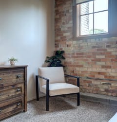 a bedroom with a chair and a brick wall and a window