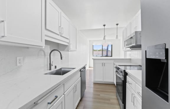 a kitchen with white cabinets and a sink and a window