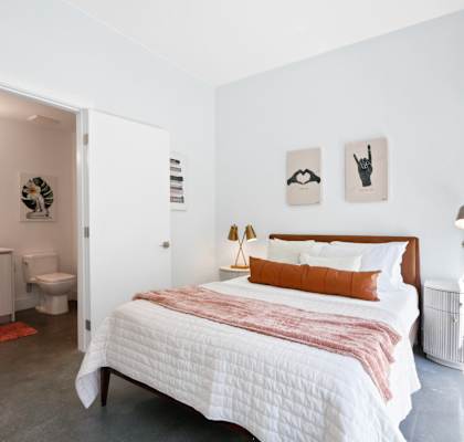 a bedroom with a bed and a bathroom in the background