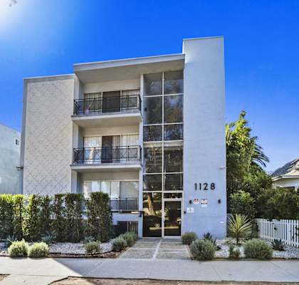a white apartment building with a sidewalk in front of it