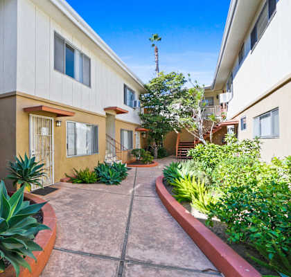 a walkway with plants in front of a building