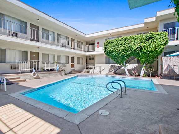 A pool in a courtyard surrounded by a white building at Oasis Apartments, Burbank