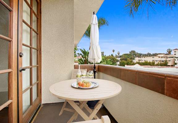A table with a plate of fruit and a glass of wine on a balcony at Darlington Apartments, Los Angeles, California