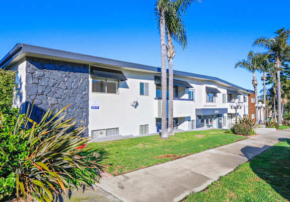 a house with a sidewalk and palm trees in front of it