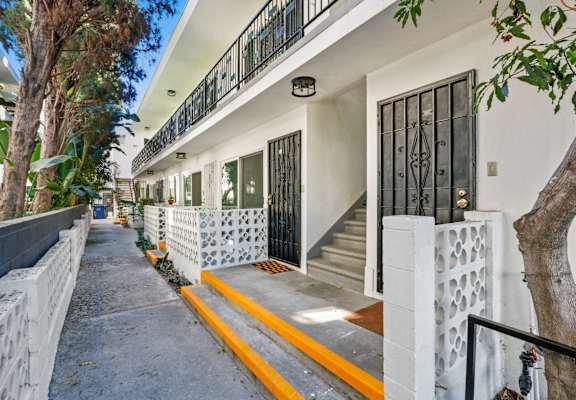 a white house with yellow steps and a black gate