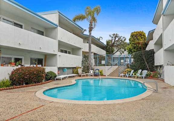 a swimming pool is in the middle of two white buildings