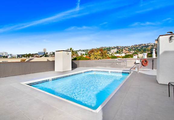 the pool is on the roof of a building with a city in the background