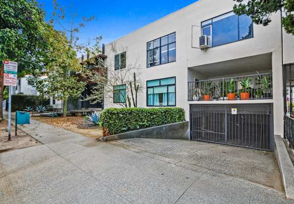 a white apartment building with a driveway and a gate