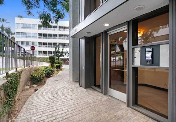 the entrance to a building with glass doors and a brick sidewalk