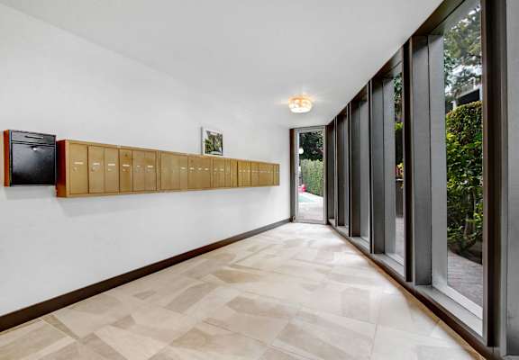 a long hallway with large windows and white walls and wooden cabinets