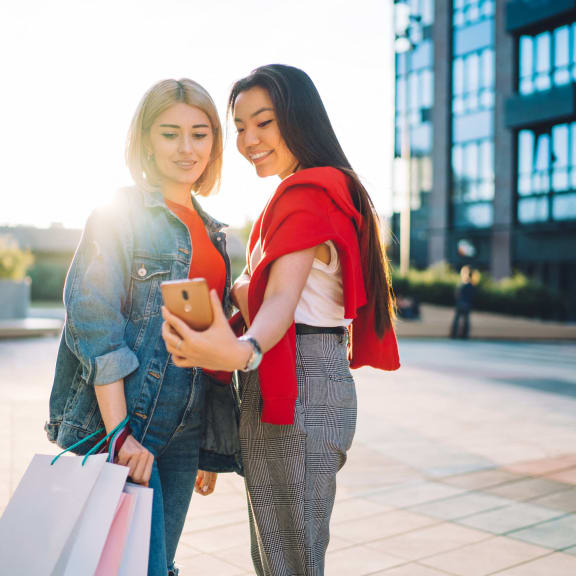two women looking at a cell phone while holding shopping bags at Viceroy Apartments, North Carolina, 27707