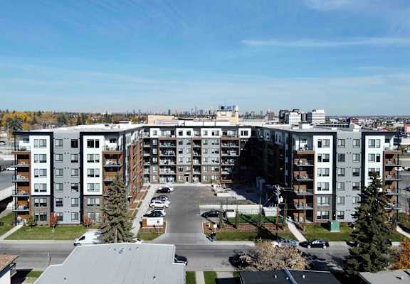 A large apartment complex with a parking lot in front.