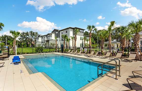 A swimming pool surrounded by palm trees and lounge chairs.
