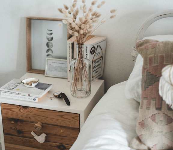 a bedroom with a bed and a nightstand with a vase of flowers