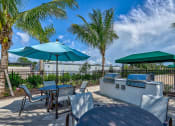 Thumbnail 14 of 49 - an outdoor patio with tables and chairs and umbrellas at Imperial Crossing Luxury Apartment Homes, Bonita Springs