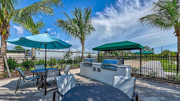 an outdoor patio with tables and chairs and umbrellas at Imperial Crossing Luxury Apartment Homes, Bonita Springs