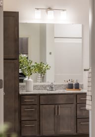 a bathroom with brown cabinets and a sink and a mirror