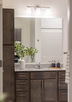 a bathroom with brown cabinets and a sink and a mirror