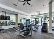 Thumbnail 24 of 49 - a gym with treadmills and other exercise equipment in a building with windows at Imperial Crossing Luxury Apartment Homes, Bonita Springs, FL