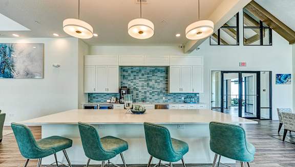 clubhouse with a kitchen and bar with blue chairs at Imperial Crossing Luxury Apartment Homes, Bonita Springs, FL