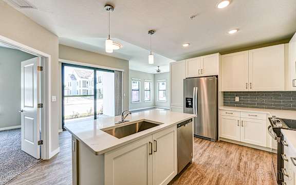 A kitchen with a stainless steel refrigerator and white cabinets.