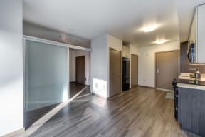 Living Room with View of Kitchen, View of Bedroom, Hardwood Inspired Floor and Black Refrigerator in Corner