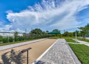 Thumbnail 11 of 49 - a walkway with a bench on the side of a sidewalk at Imperial Crossing Luxury Apartment Homes, Bonita Springs, Florida