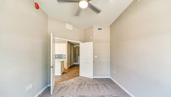 an empty room with a ceiling fan and a hallway to a bathroom at Imperial Crossing Luxury Apartment Homes, Bonita Springs, Florida