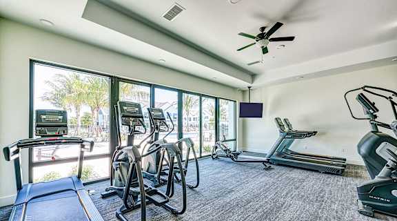 the fitness room has plenty of cardio equipment and windows at Imperial Crossing Luxury Apartment Homes, Bonita Springs