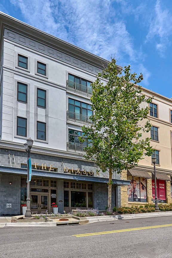 A street view of a building with a parking area in front.