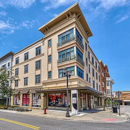 A street view of a multi-story building with a clear blue sky above.