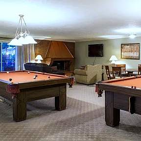 A room with two pool tables and a television.