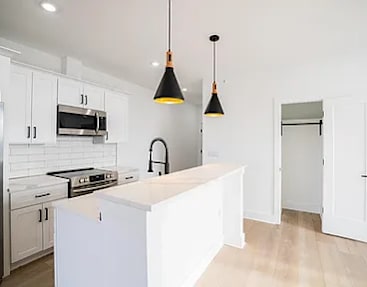A kitchen with white cabinets and a white island.