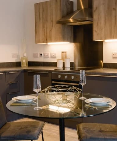 a kitchen with a glass table with plates on it at Vox Apartments, Manchester