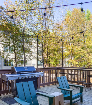 a picnic table and chairs on a deck with a grill