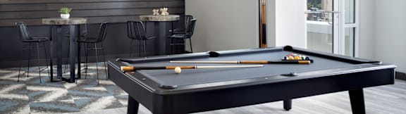 A pool table with a red cloth and a white cue ball.